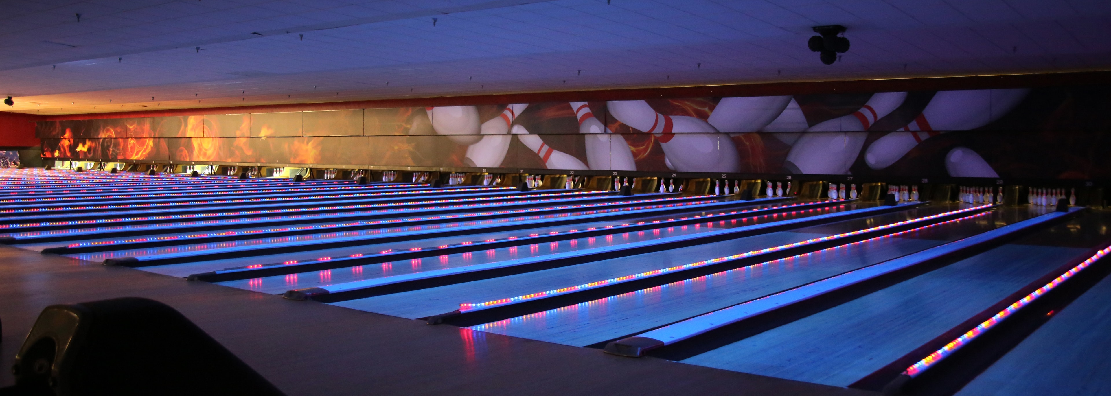Bowling alley large-format wall mural with bowling pin graphics and neon lane lighting by Architectural Wraps